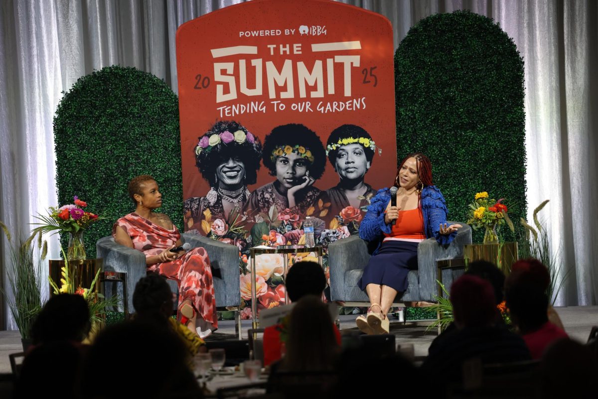 To the left, Ashlei Spivey listens as Pulitzer Prize winning journalist Nikole Hannah Jones answers questions for a panel.  Attendees watched from their tables. Jones said, “Unfortunately the normative state of this country is injustice.” 