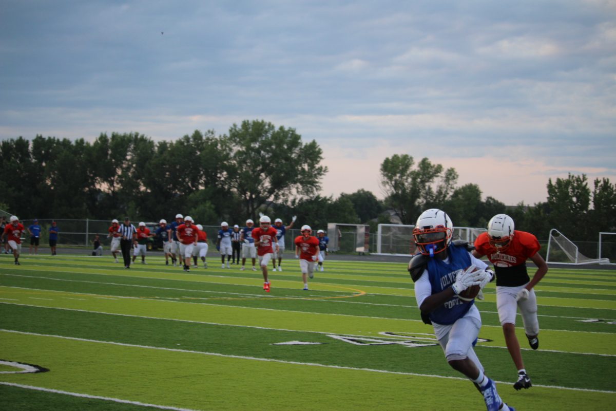 
Varsity players run the ball as Junior Varsity player chases him. Players from both teams followed in the back
