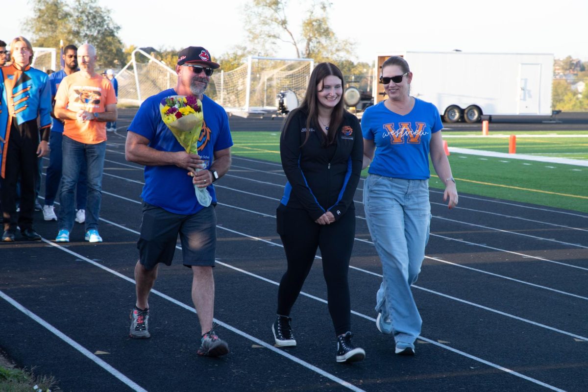 Brenna McKinley, 12, walks across the track to be recognized as a senior. Colorguard was one of six groups recognized during the senior night.